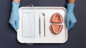 a face mask, scaler, dental mirror, and a teeth model being prepared for a dental treatment